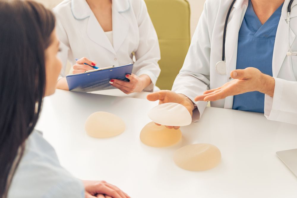 Patient with medical professionals and breast implants on table